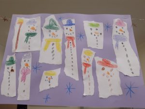 Na jasnofioletowym tle umieszczono kawałki papieru, na którcy widnieje narysowane bałwanki.