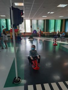 Zdjęcie wykonane na zajęciach w toruńskim WORDzie przedstawia uczennicę siedzącą na mini rowerku przed sygnalizacją świetlną.