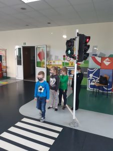 Zdjęcie wykonane na zajęciach w toruńskim WORDzie przedstawia uczniów ustawionych w rzędzie i przechodzących przez pasy na zielonym świetle.