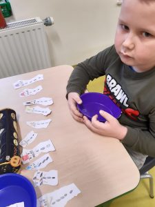 Na stoliku przed uczniom leżą rozłożone kawałki papieru z narysowanymi bałwankami.