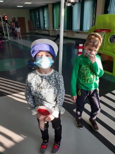 Zdjęcie wykonane na zajęciach w toruńskim WORDzie przedstawia dwójkę uczniów stojących w sali edukacyjnej. Uczennica trzyma w dłoni lizak a na głowie ma czapkę policjanta.