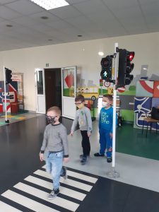 Zdjęcie wykonane na zajęciach w toruńskim WORDzie przedstawia troje uczniów przechodzących w rzędzie po pasach na zielonym świetle.