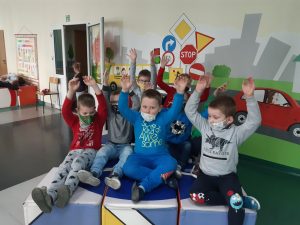 Zdjęcie wykonane na zajęciach w toruńskim WORDzie przedstawia uczniów siedzących z podniesionymi rękoma na połączonych, kolorowych, sześciennych kostkach.