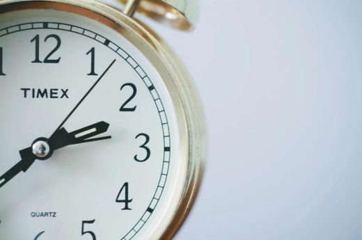 Na białym tle fragment zegarka ze złotą kopertą.