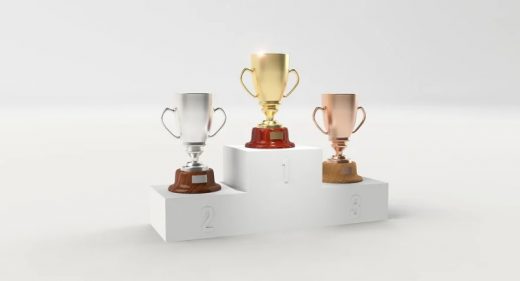 Grafika przedstawia białe podium, na którym ustawiono trzy puchary.