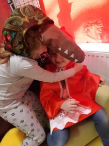 Scena z bajki o czerwonym kapturku - Wilk przebrany za babcię obejmuje czerwonego kapturka.