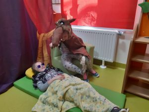 Zdjęcie przedstawia scenę z czerwonego kapturka - na podłodze leży przebrana za babcię uczennica a obok niej siedzi uczeń przebrany za wilka..