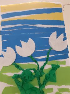 Praca ucznia. Na tle pasków z kolorowego papieru widnieją trzy papierowe przebiśniegi.