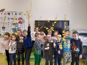 Na zdjęciu widoczni są wszyscy uczniowie trzymający w dłoniach zrobione przez siebie gałązki z żółtymi kwiatkami.