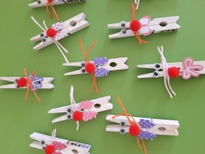 Na zielonym tle umieszczono osiem białych klamerek przybranych kokardkami i czerwonymi pomponami w miejscu nosa tak by wyglądały jak króliczki.