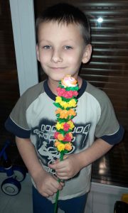 Uczeń trzyma w obu dłoniach przed sobą palmę wielkanocną.