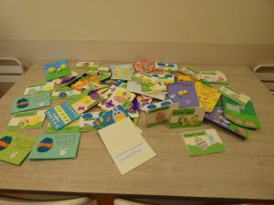 Na stole leżą porozrzucane kartki świąteczne przygotowane przez uczniów.