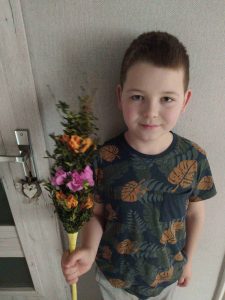 Uczeń trzyma w prawej dłoni wykonaną przez siebie palmę wielkanocną.