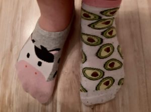 Na drewnianej podłodze widoczne dwie stopy w różnych skarpetkach we wzorki.