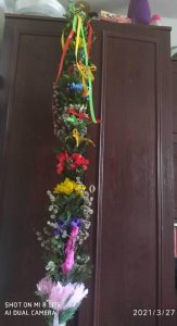 Na tle brązowej szafy różnokolorowa palma wielkanocna.