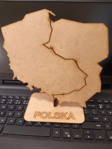 Na klawiaturze laptopa ustawiono model mapy Polski jeszcze nie upiększony przez uczniów. Model stoi na podstawce z napisem Polska . Na mapie zaznaczono tylką główną rzekę - Wisłę.