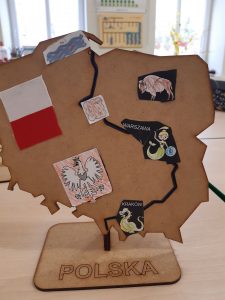 Zdjęcie przedstawia gotowy model mapy Polski na której uczeń wykleił naklejki, na których znajdują się: flaga, godło, syrenka warszawska, smok Wawelski.