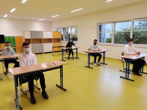 Uczniowie siedzą przy ławkach - czekają na egzamin.