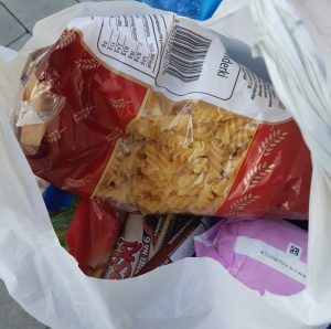 Zdjęcie torby z darami dla mieszkańców Ukrainy - w środku makaraon, słodycze oraz inne produkty żywnościowe.