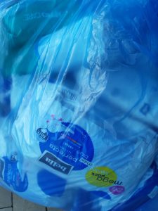 Zdjęcie plastikowej przezroczystej torby przez którą widać opakowania z podpaskami znajdującymi się wewnątrz niej.