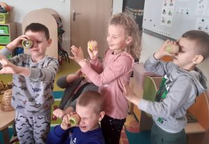 Dzieci spoglądają przez male lunety na swoje dłonie.