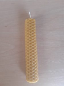 Zdjęcie świeczki zrobionej z pszczelego wosku - świeczka jest prosta z przetłoczenie w kratkę.