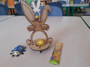 Zdjęcie złożonego modelu zajączka z umieszczonym w podstawie czekoladowym jajeczkiem oraz czekoladową biedronką i zajęczkiem ustawionymi obok modelu.