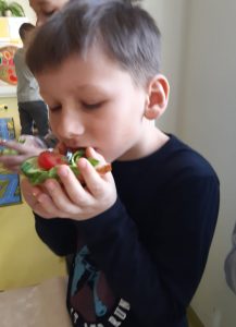 Uczeń je zdrową kanapkę z sałatą i pomidorem.