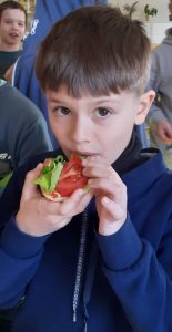 Uczeń je zdrową kanapkę z sałatą i pomidorem.