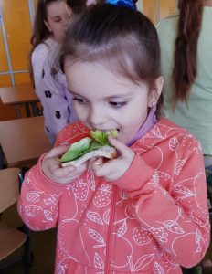 Uczennica je kanapkę z sałatą.