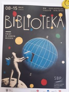 Plakat promujący bibliotekę. Czarnym tle niebieska kula symbolizująca ziemię oraz postać stojąca na księżycu i wyciągająca z ziemi jej fragment w kształcie książki. W okól kolorowe koła a nad wszystkim napis )*-15 Maja 2022 XIX OGÓLNOPOLSKI TYDZIEŃ BIBLIOTEK" Pod spodem duży napis BIBLIOTEKA oraz po prawej stronie motto ŚWIAT W JEDNYM MIEJSCU. W prawym dolnym rogu Napis Stowarzyszenie Bibliotekarzy Polskich a nad nim logo stowarzyszenia.