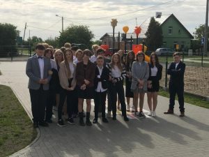 Ósmoklasiści pozują do grupowego zdjęcia na szkolnym boisku.