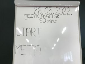 Zdjęcie białej tablicy z jednej z sal egzaminacyjnej z napisem" 26.05.2022. JĘZYK ANGIELSKI 90 minut START META".