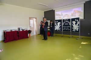 Wójt gminy Łysomice przemawia na tle dekoracji przygotowanej na galę absolwenta.