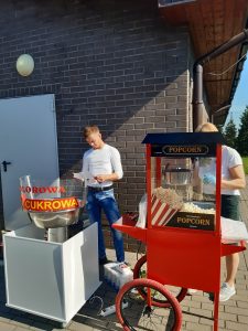 Zdjęcie maszyn do robienia popcornu i waty cukrowej oraz stojącej za nią obsługi.