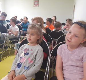 Zbliżenie na uczniów ogladających przedstawienie. Dzieci siedzą na krzesełkachustawionych na sali teatralnej.