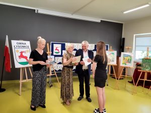 Pani Dyrektor i Wójt Gminy Łysomice wręczają dyplom jednej z nagrodzonych uczennic. Obok stoi nauczycielka, która była jedną z organizatorów konkursu.