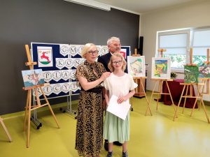 Pani Dyrektor i wójt pozują do zdjęcia z jedną z nagrodzonych uczennic. Dziewczynka trzyma w ręku dyplom.