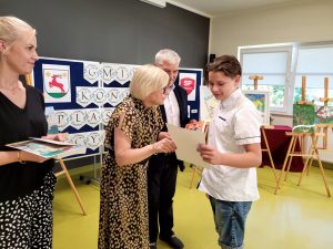 Pani Dyrektor wraz z Panem Wójtem wręczają uczniowi dyplom i nagrodę książkową za udział w gminnym konkursie plastyczno - recytatorskim.