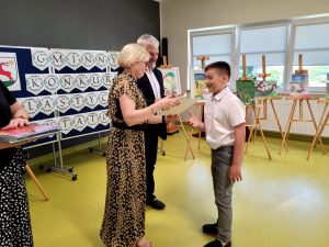 Pani Dyrektor wraz z Panem Wójtem wręczają uczniowi dyplom i nagrodę książkową za udział w gminnym konkursie plastyczno - recytatorskim.