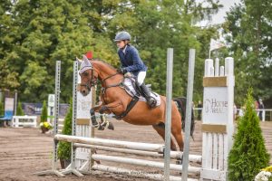 Uczennica Maja Iwińska siedzi na koniu przeskakującym przez przeszkodę.