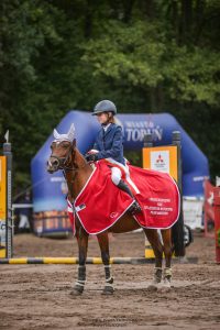 Uczennica Maja Iwińska siedzi na koniu przybranym w czerwona pelerynę.