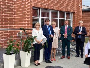Przy budynku szkoły stoja w rzędzie Pani Dyrektor i przedstawiciele gminy. Zdjęcie wykonane podczas inauguracji roku szkolnego 2022/2023.