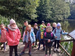 Uczniowie zerówki pozują na pomoście przy stawie na barbarce.
