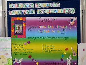 Zdjęcie plakatu kandydatki do małego Samorządu Uczniowskiego. W lewym górnym rogu zdjęcie kandydtki, a obok niego na kolorowym tle napisy: "Cześć ! Jestem LENA STAIMIERSKA CHODZEDO KL. II kandyduje do małego Samorządu Uczniowskiego. Moje pomysły: 1. Piżama party 2. Dzień gry w karty pokemon 3. Częstsze wycieczki do kina 4. Dzień z telefonem 5. Dzień pizzy 6. Nauka tańca 7. Pomoc w odrabianiu zadania 8 domowego". U dołu plakatu napis:"Liczę na Twój głos !". Plakat ozdobiony kolorowymi naklejkami.