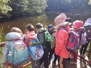 Uczniowie oddziału przedszkolnego stoją na pomoście przy stawie na barbarce i spoglądaja w stronę wody.