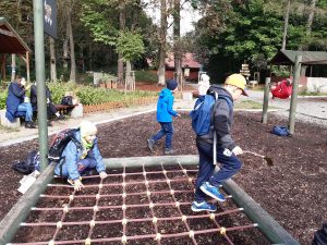 Uczniowie podczas zabawy na placu przy szkoleleśnej na Barbarce, Na pierwszym planie widać zamontowaną przy ziemi siatkę z dużymi dziurami, po której próbuje przejść dwójka uczniów.