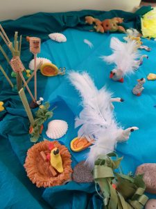 Zdjęcie fragmentu makiety przedstawiającej jezioro, a na nim łabędzie wykonane z plasteliny i ozdobione bialymi piórkami.