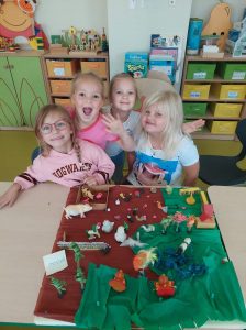 Cztery uczennice pozują do zdjęcia przy ustawionej przed nimi kolorowej makiecie ze zwierzątkami.