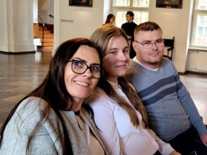 Pani Iwona Szymańska, Paulina Ernest i jej tata siedząc obok siebie pozują do zdjęcia.